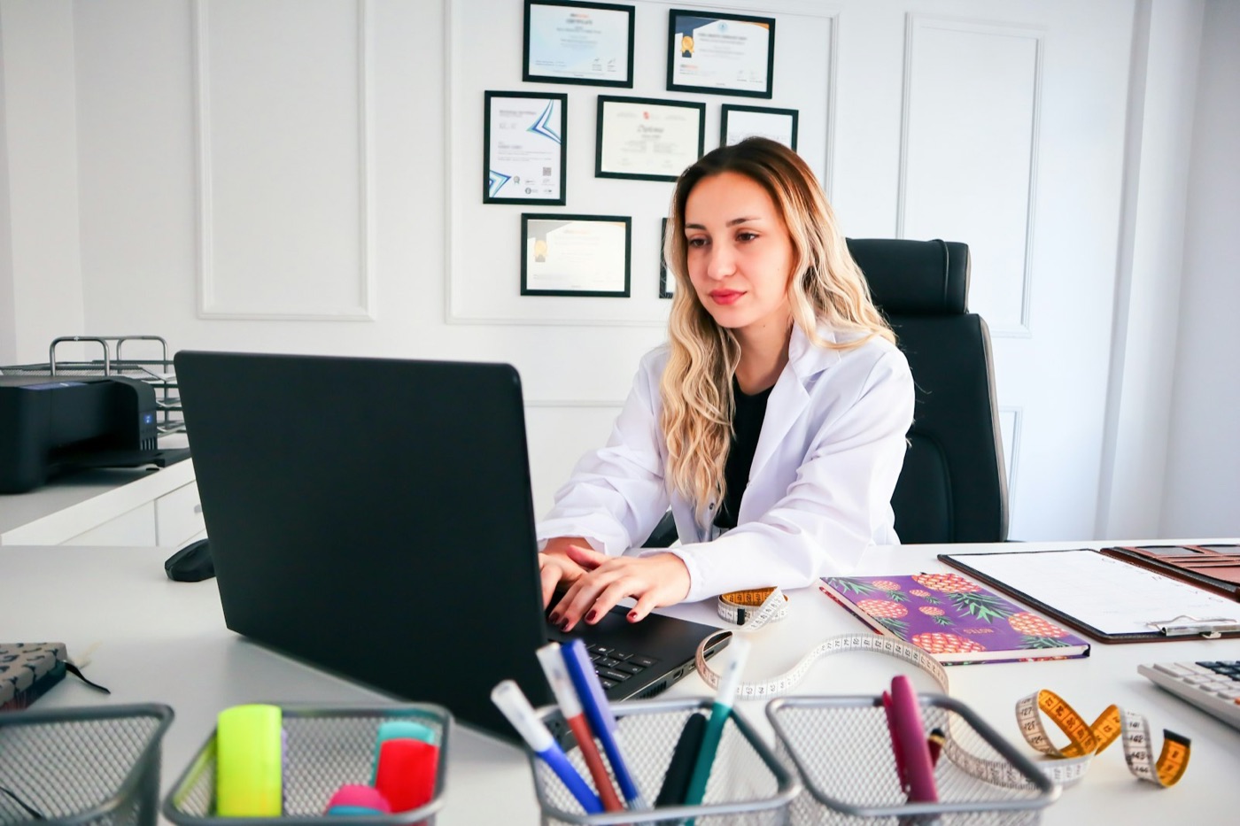 A medical professional drafting a document on a laptop at her desk