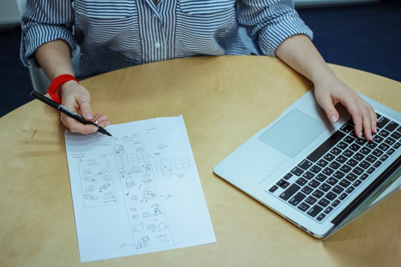 A writer reviews notes on paper beside a laptop