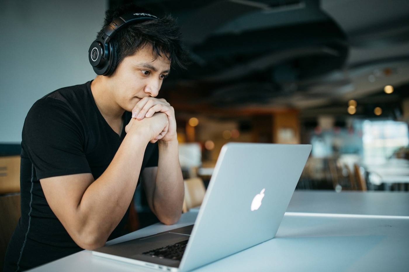 A learner with headphones follows a training module on a laptop
